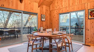 a dining room with a table and chairs and windows at 5BDR Hot Tub Deck Firepit Mins to Village Lake The Hilltop by AvantStay in Lake Arrowhead
