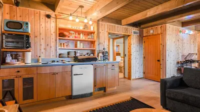 a kitchen with wooden cabinets and a white refrigerator at 5BDR Hot Tub Deck Firepit Mins to Village Lake The Hilltop by AvantStay in Lake Arrowhead