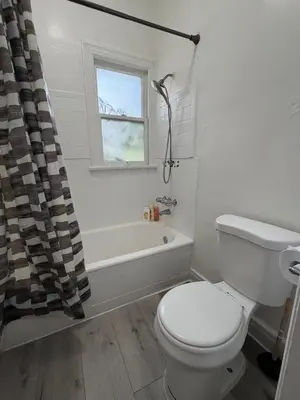 a bathroom with a toilet and a tub and a window at Westlake MacArthur Park Studio in Los Angeles