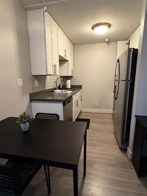a kitchen with white cabinets and a table and a refrigerator at Steps from The Hollywood Walk of Fame in Los Angeles