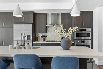 a kitchen with a white counter with blue chairs at Amethyst Sky Loft - Elevated Two-Story Waterfront in Los Angeles