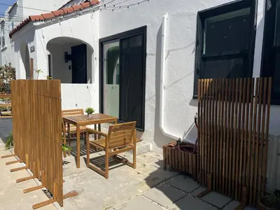 a patio with a wooden table and chairs next to a house at East Hollywood Modern Spacious Bungalow in Los Angeles