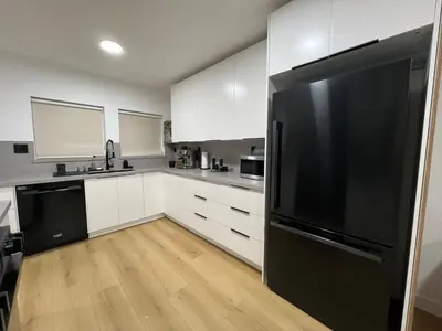 a kitchen with white cabinets and a black refrigerator at East Hollywood Modern Spacious Bungalow in Los Angeles
