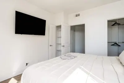a white bedroom with a bed with a flat screen tv on the wall at Sleek Marina Den Central Gym Pool King Bed in Los Angeles