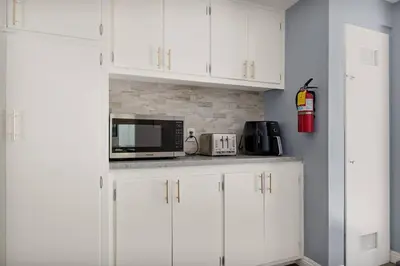 a white kitchen with white cabinets and a microwave at Skiers Crest - Hot Tub, Yard, Near Lake & Slopes in Big Bear Lake