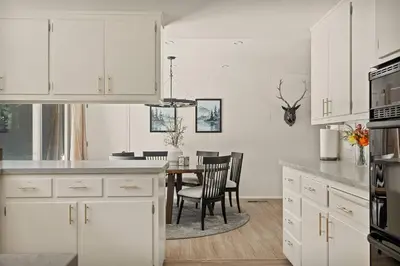a kitchen with white cabinets and a table with chairs at Skiers Crest - Hot Tub, Yard, Near Lake & Slopes in Big Bear Lake