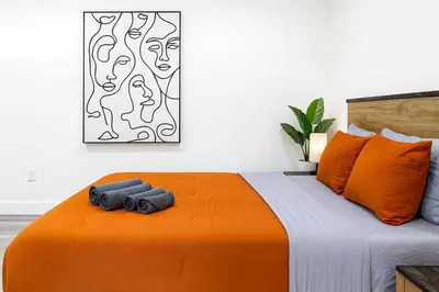a bedroom with an orange bed with two pillows at The Harvard Modern Retreat LA in Los Angeles