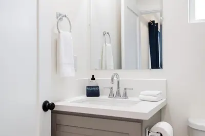 a white bathroom with a sink and a mirror at The Harvard Modern Retreat LA in Los Angeles