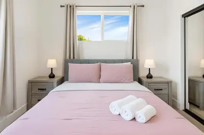 a bedroom with a pink bed with two towels at The Harvard Modern Retreat LA in Los Angeles