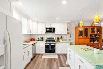 a kitchen with white cabinets and a stove top oven at Elsa House in Warner Center Plaza One Heliport
