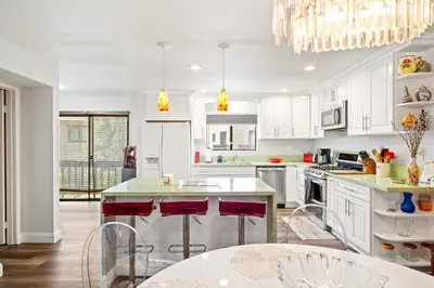 a kitchen with white cabinets and red bar stools at Elsa House in Warner Center Plaza One Heliport