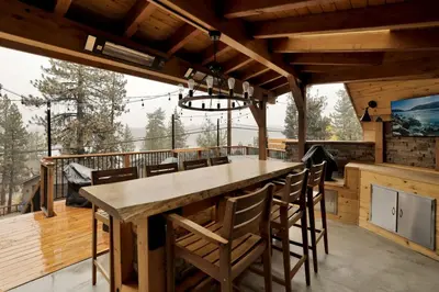 an outdoor kitchen with a large wooden table and chairs at Stairway to Heaven at Big Bear- Million Dollar Lake Views - Modern Luxury Chalet w/ Hot Tub in Big Bear Lake