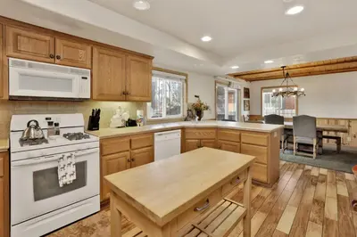 a kitchen with wooden cabinets and a white stove top oven at Brownie Resort Your Walk-to-Summit Getaway Family's Snowboarders Skiers in Big Bear Lake