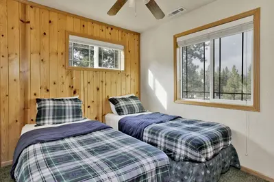 two beds in a room with wooden walls and windows at Brownie Retreat Walk-to-Summit Mountain Getaway for Snowboarders & Skiers in Big Bear Lake