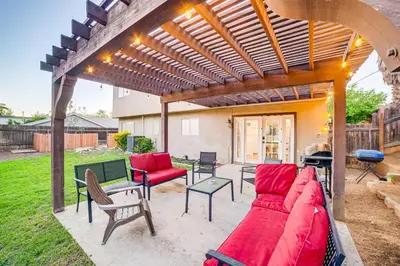a patio with a red couch under a wooden pergola at Home 1 Mi to UC Riverside Families Welcome! in Riverside