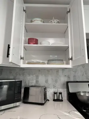 a kitchen with white cabinets and a microwave and plates at Cozy Home near Beaches, LAX, SoFi, Intuit Dome,405 in Hawthorne