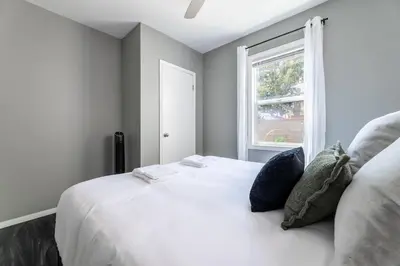 a white bed in a room with a window at Hawthorne Haven Spacious 4BR Retreat in Hawthorne