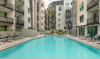 a large swimming pool with chairs and buildings at BOHO Style Home LA -Free Parking 10min To Cedars in Los Angeles