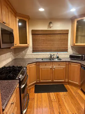 a kitchen with wooden cabinets and a stove top oven at Cozy Home in Picturesque LA Near Major Attractions