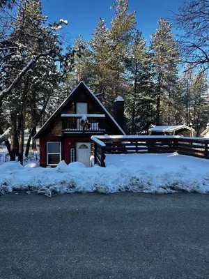 a house with a fence in the snow at Snuggle Inn Cabin in Running Springs