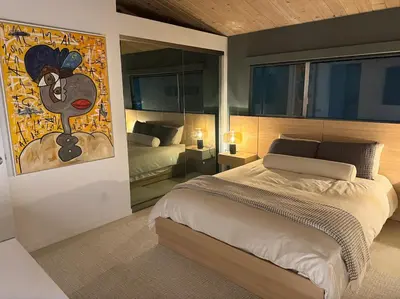 a bedroom with a bed and a painting on the wall at Hillside Luxury MidCentury Modern Spa Retreat View in Los Angeles