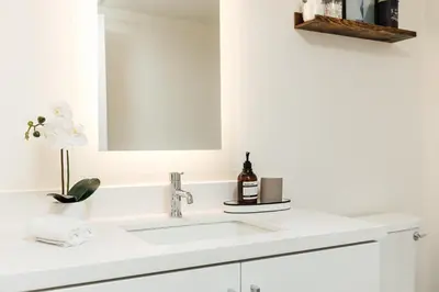 a white bathroom with a sink and a mirror at Beautiful 1BR with City Views in Los Angeles