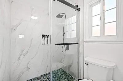 a white bathroom with a shower with a glass door at Stylish Retreat Large Living Space & Bright Suites in Norwalk