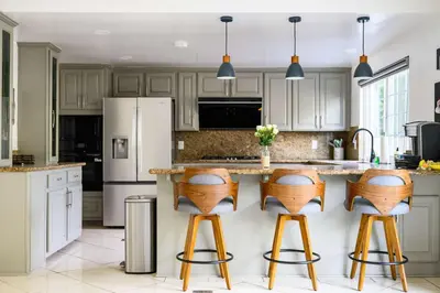 a kitchen with white cabinets and wooden bar stools at Cozy Full Suites Bright & Private Great Value in Norwalk