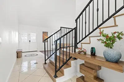 a living room with stairs and a vase with flowers at Upgraded Queen Suite Private Ensuite Bright Stay in Norwalk