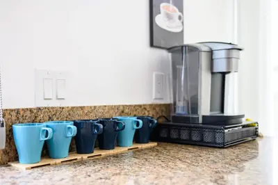 a row of blue coffee cups sitting on a kitchen counter at Premium Queen Room Private Ensuite Bright in Norwalk