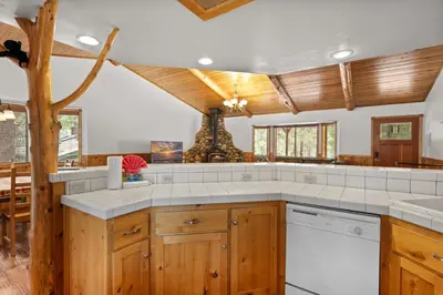 a kitchen with white counter tops and wooden cabinets at Leaf & Needle - Walk to Lake & Village, Picnic Table, Single Story, Fenced Yard in Big Bear Lake