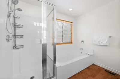 a white bathroom with a shower and a tub at Leaf & Needle - Walk to Lake & Village, Picnic Table, Single Story, Fenced Yard in Big Bear Lake