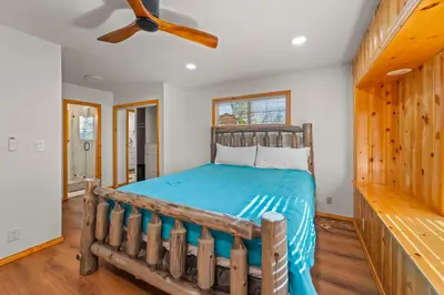 a bedroom with a wooden bed and a ceiling fan at Log Cabin Dream - Log Cabin, Walk to Lake, Fireplace, Deck, BBQ in Big Bear Lake