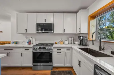 a kitchen with white cabinets and a stove top oven at Log Cabin Dream - Log Cabin, Walk to Lake, Fireplace, Deck, BBQ in Big Bear Lake