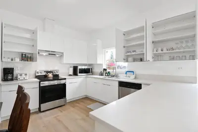 a white kitchen with white cabinets and black appliances at New Family House Fanstic View Azusa in Azusa