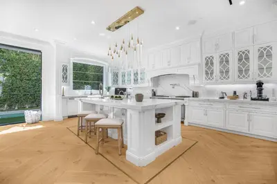 a kitchen with white cabinets and a island with bar stools at Spaulding Ave Farmhouse in Los Angeles