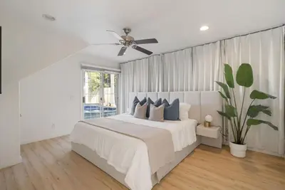 a white bedroom with a bed and a ceiling fan at Sunlit Oasis with Heated Pool and Jacuzzi 20 minutes to Disneyland in Placentia