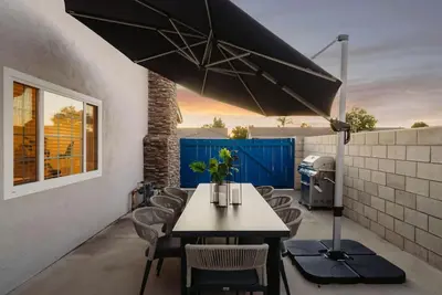 a patio with a table and chairs and an umbrella at Sunlit Oasis with Heated Pool and Jacuzzi 20 minutes to Disneyland in Placentia