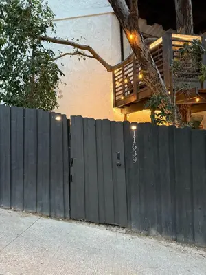 a black fence next to a house with a tree at Private getaway in Studio City Hills universal in Los Angeles