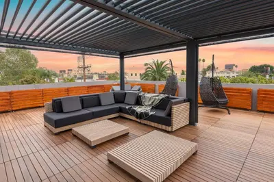 a patio with a couch and tables on a deck at Ultra Luxe Estate With Pool and Stunning 360 LA Views in Los Angeles
