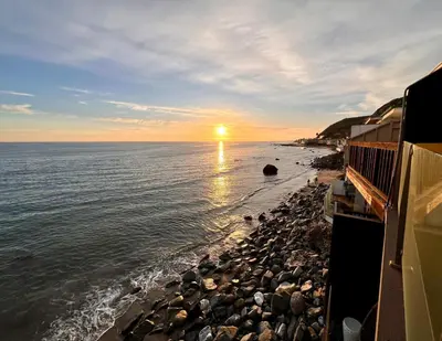 a sunset on a rocky beach with the ocean at Malibu Waterfront Gallery with Private Beach Access in Malibu Beach