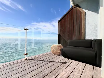 a black couch sitting on a wooden deck with the ocean at Malibu Waterfront Gallery with Private Beach Access in Malibu Beach