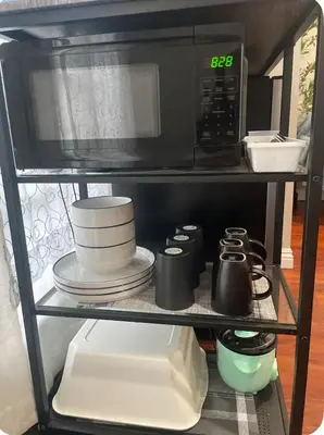 a microwave on a shelf with plates and utensils at The stay go in Gardena