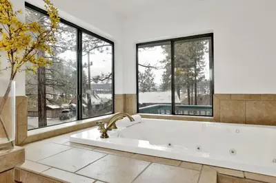 a large white bath tub in a room with windows at Vivienda De Osos Walk to the Lake Spacious Fawnskin Retreat Chalet in Fawnskin