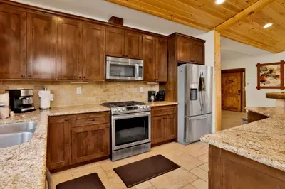 a kitchen with wooden cabinets and stainless steel appliances at Morning Star Log Cabin at Big Bear Ultra-Modern Castle Glen Mountain Chalet in Big Bear Lake