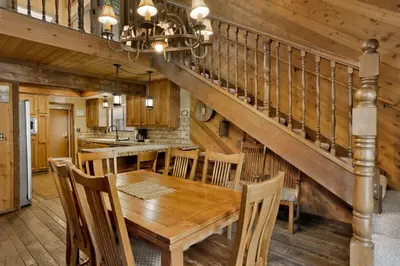 a dining room with a wooden table and a staircase at Crystal Pines at Big Bear Lake Walk to Boulder Bay Park Family-Friendly Retreat in Big Bear Lake