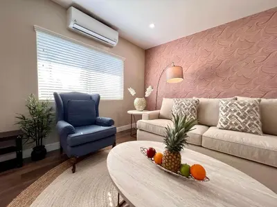 a living room with a couch and a table with fruit on it at Golden Downey Designer Abode - Poolside Suite in Downey