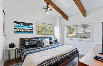 a bedroom with a bed and two windows at Relaxing 4 bedroom Mountain Stay in Lake Arrowhead