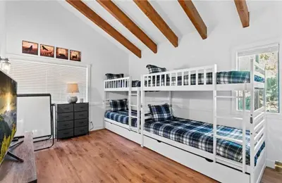 two white bunk beds in a white room with wood floors at Relaxing 4 bedroom Mountain Stay in Lake Arrowhead