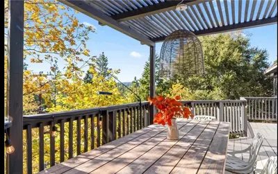 a vase of flowers on a table on a deck at Relaxing 4 bedroom Mountain Stay in Lake Arrowhead